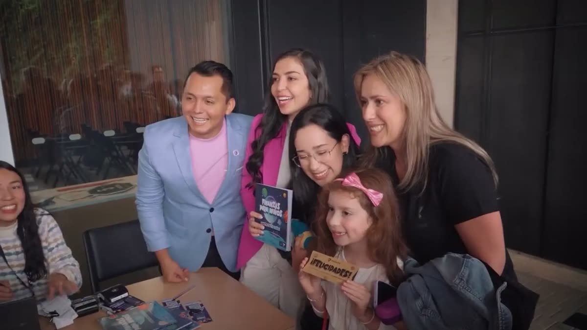 Ana María Forero Pantoja y Juan Manuel Jiménez firmando ejemplares de &laquo;Finanzas para niños&raquo; en la Feria del Libro de Bogotá de 2024, junto a una niña que sostiene un boleto dorado con el logotipo de Poolex.